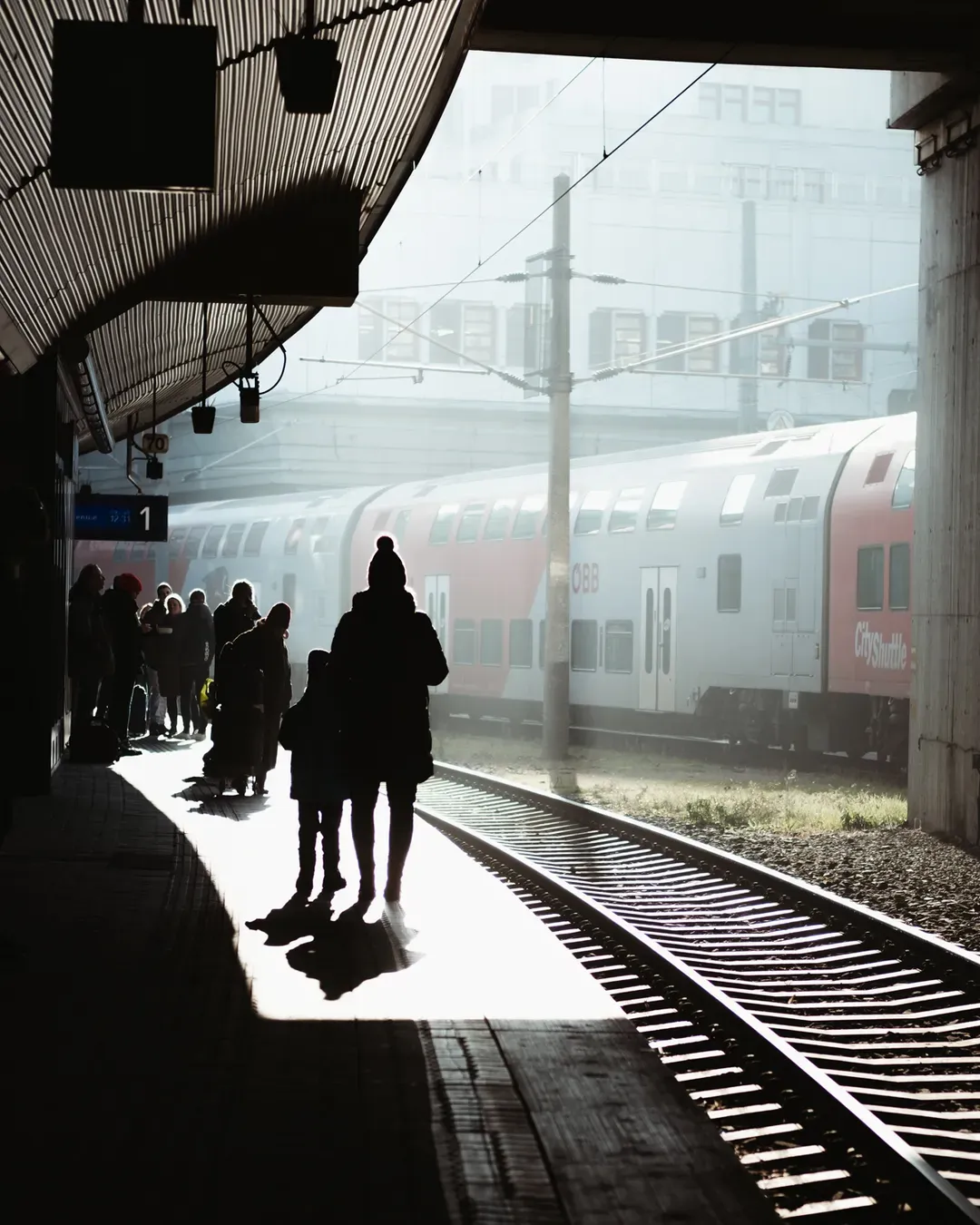Silhouetten von Reisenden am Bahnsteig im Gegenlicht