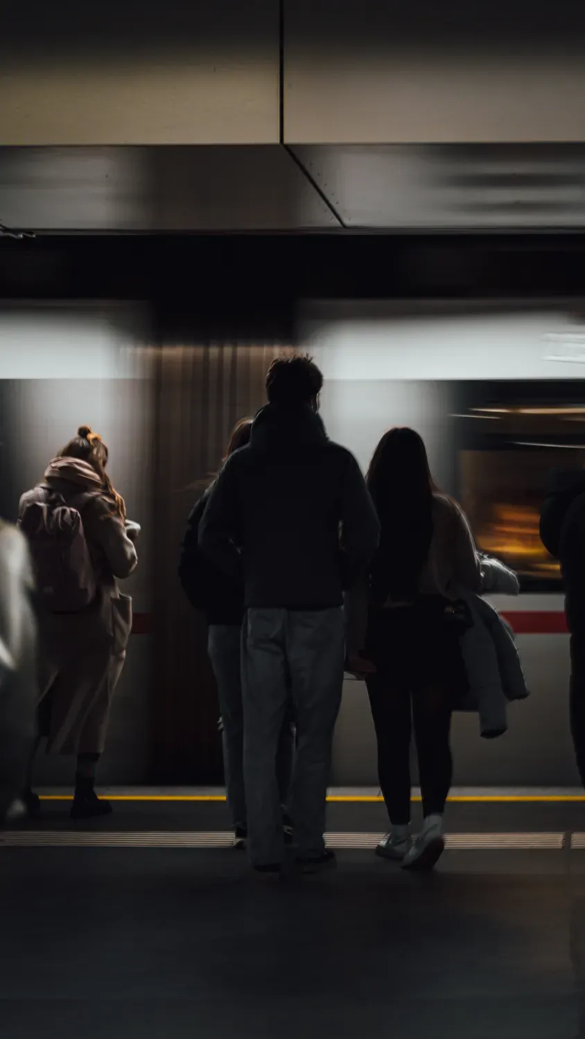 Menschen warten am Bahnsteig vor einfahrender U-Bahn