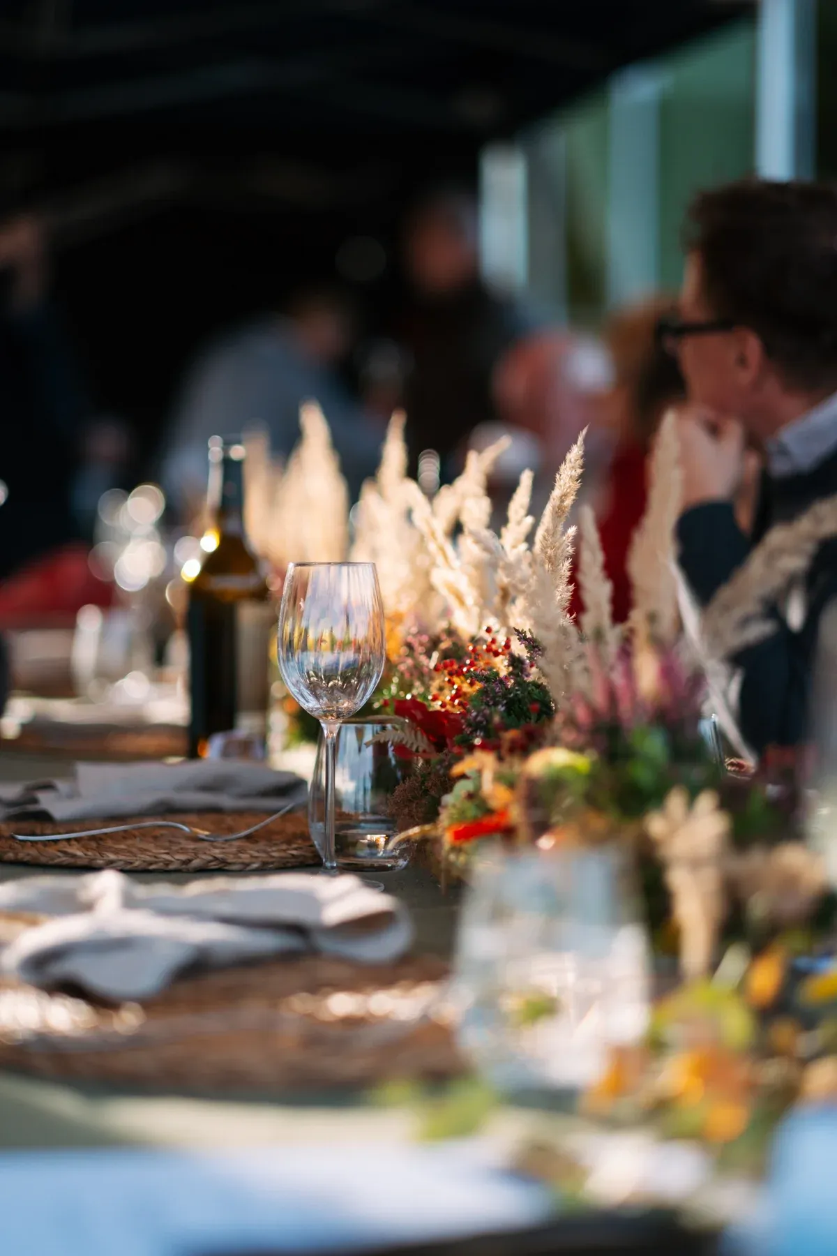 Festlich gedeckte Tafel mit Gästen im Hintergrund