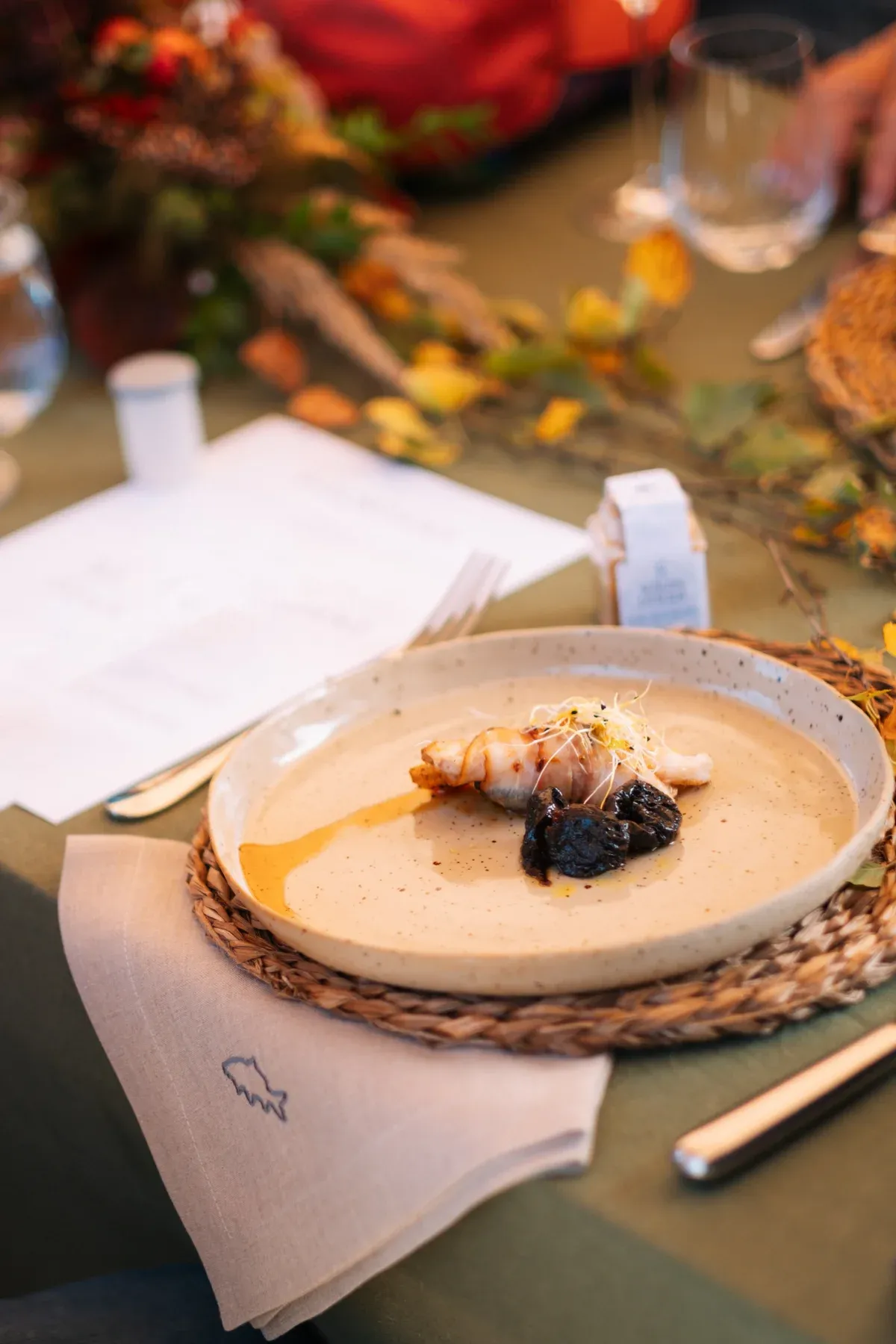 Angerichteter Gang auf Keramikteller an herbstlich dekorierter Tafel