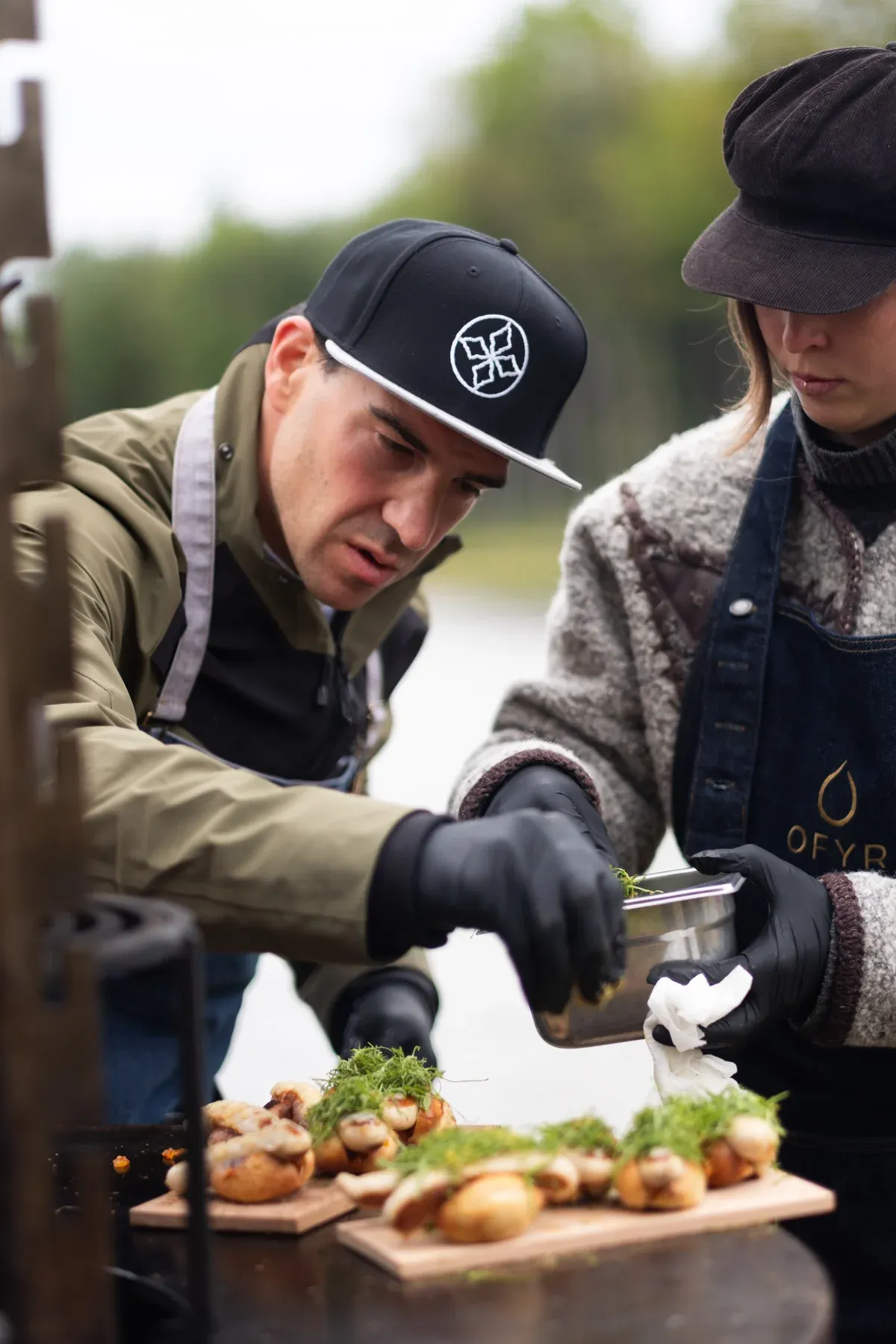 Zwei Köche richten Fingerfood auf Holzbrettern im Freien an