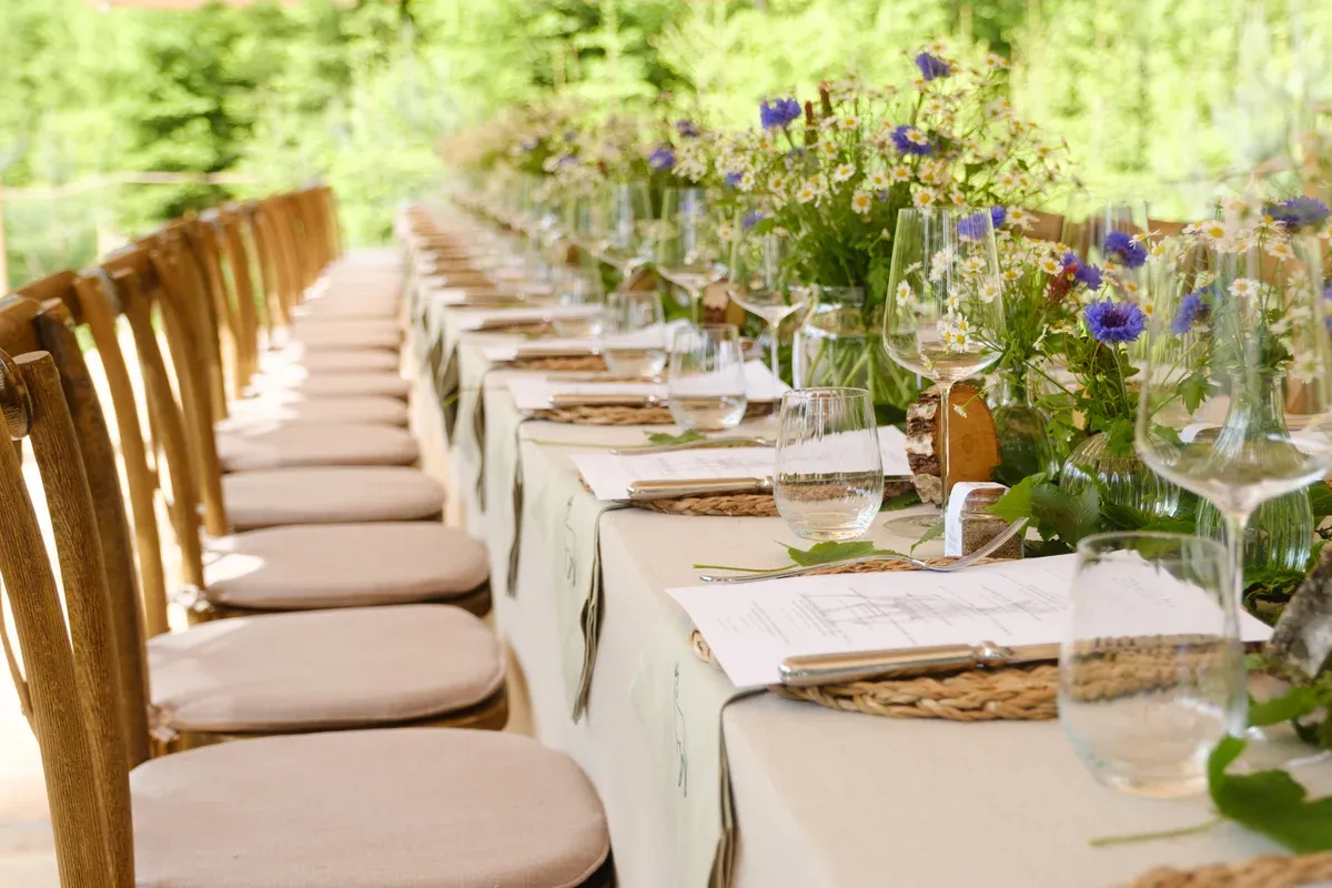 Lange Festtafel mit Wiesenblumen mitten im Wald